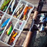 Fishing lures in a tackle box next to a spinning rod