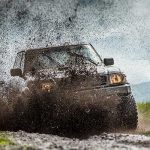 Jeep driving off-road spraying mud from tyres
