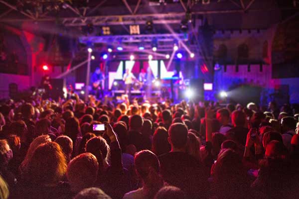 Silhouettes crowd in front of brightly lit stage